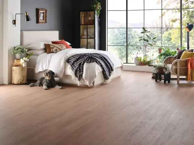 Bright bedroom with a dog, mountain views, and wood-look flooring.