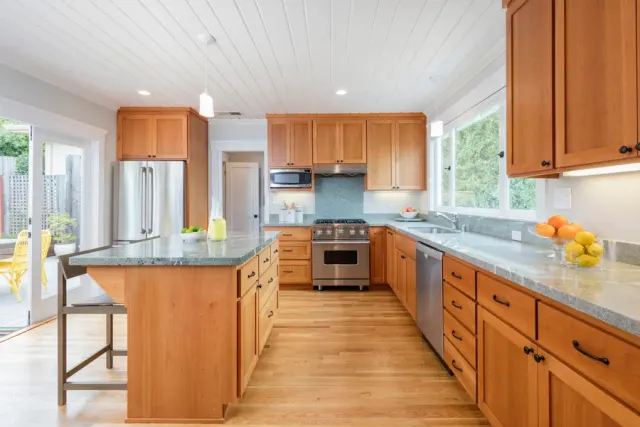Kitchen with wood cabinetry, granite counters, and light wood-look flooring.